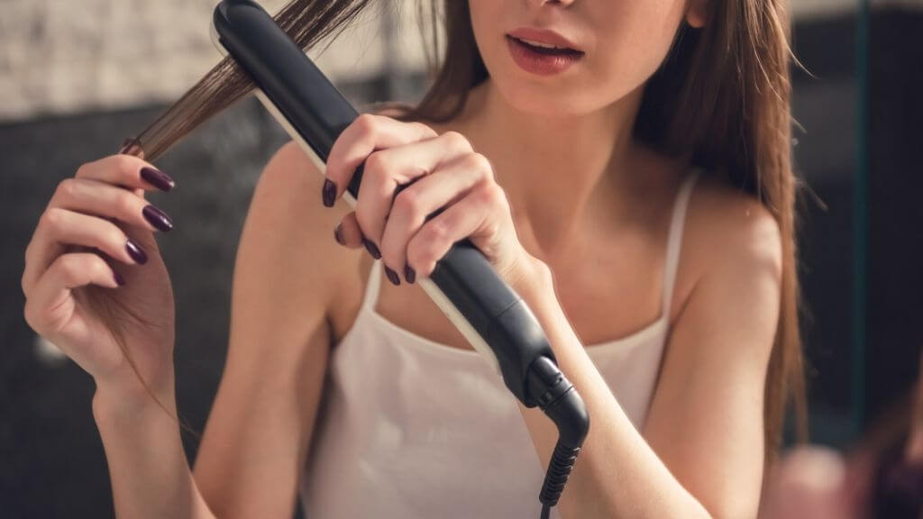 A woman straightening her hair.