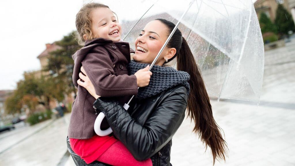 A woman holding her child under an umbrella