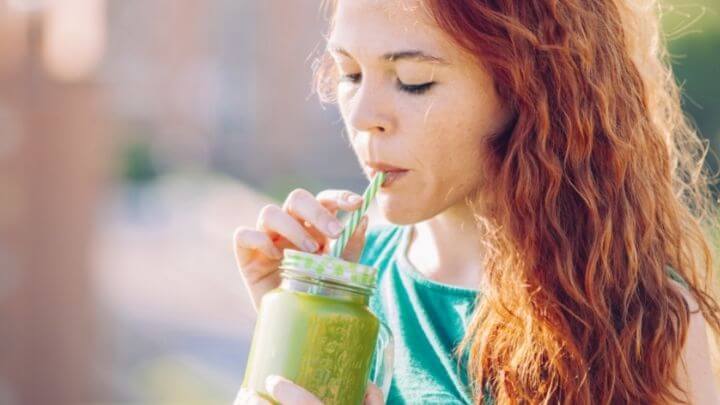 A woman enjoying a green smoothie