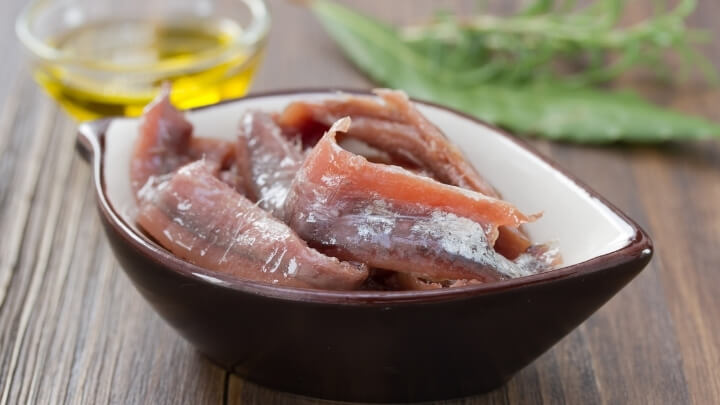 Anchovies in a dish with oil and herbs