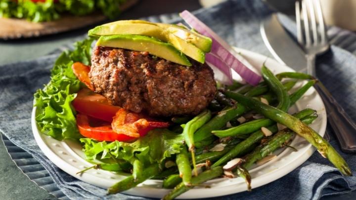 Freshly grilled avocado bacon paleo burger with green beans