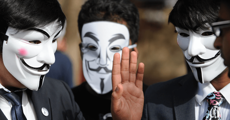 Three men wearing Guy Fawkes masks talking to each other