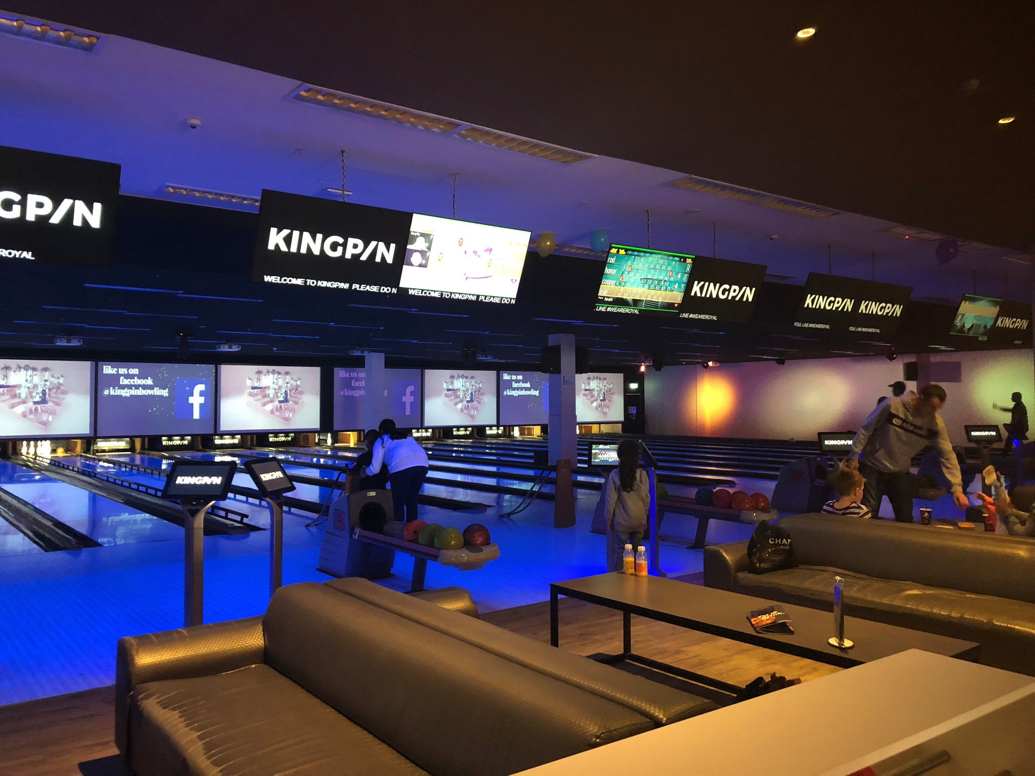 A dark lit bowling alley. A series of TV screens say "Kingpin".