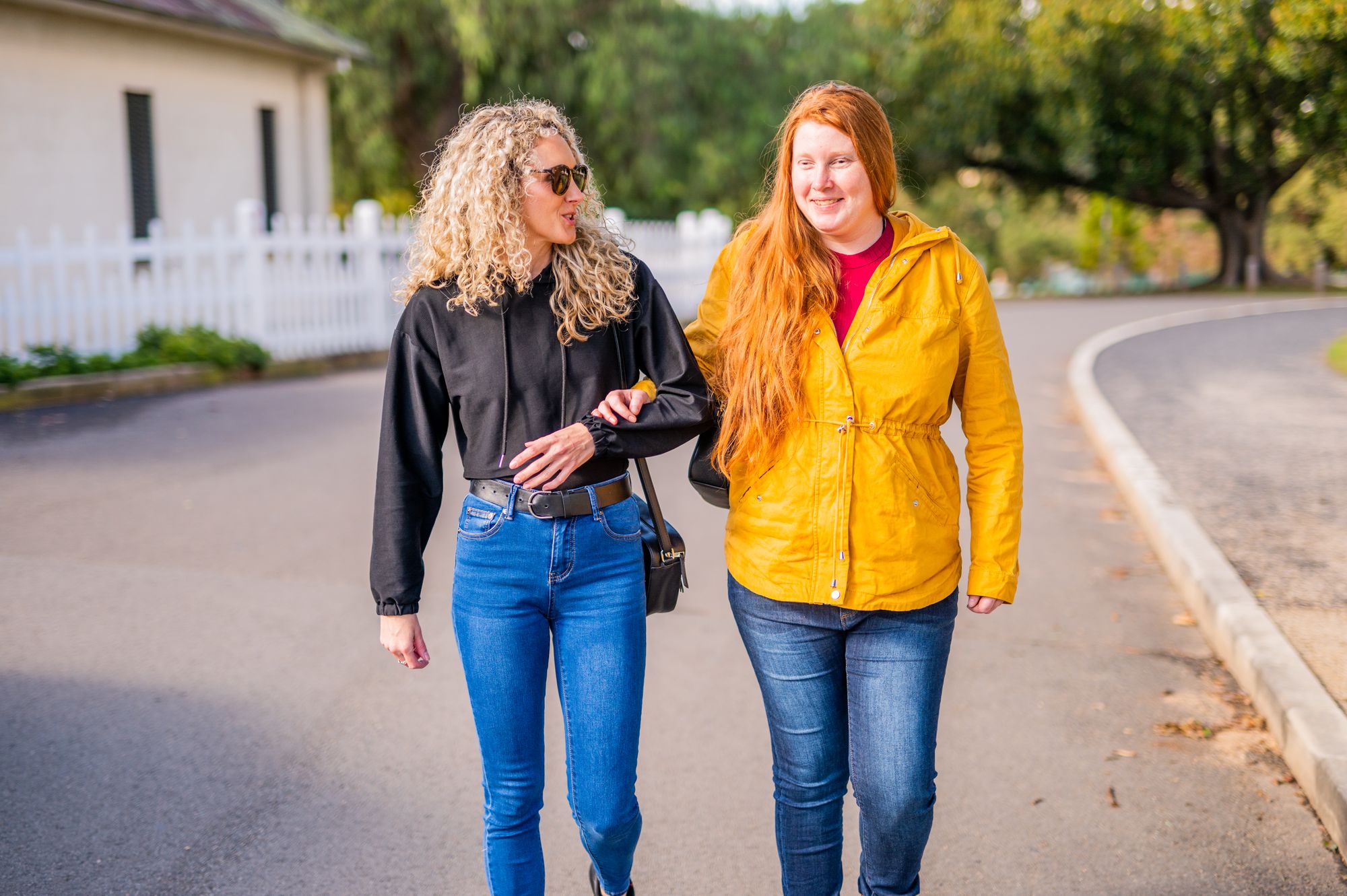 Two women walking down a street with their arms linked