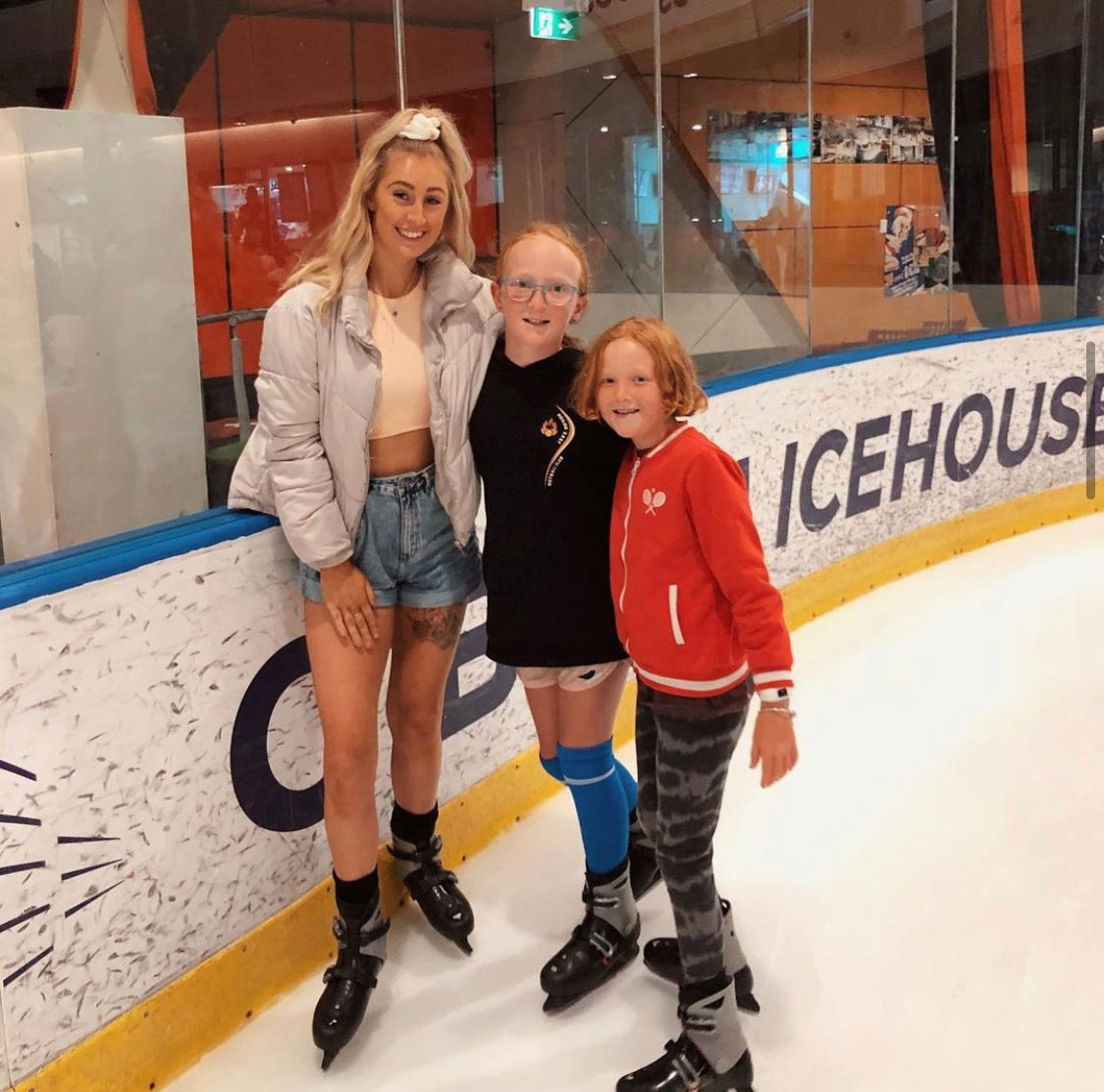 A woman and two girls at an ice skating rink