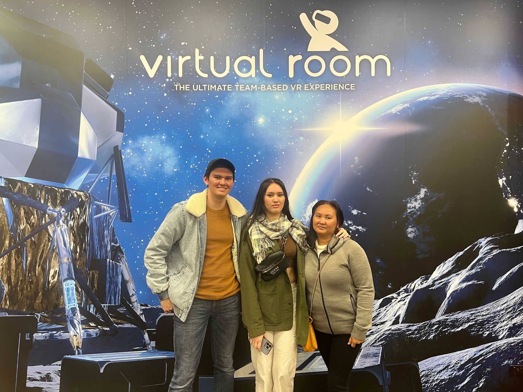 Philip and 2 women stand in front of a sign that says "virtual room"
