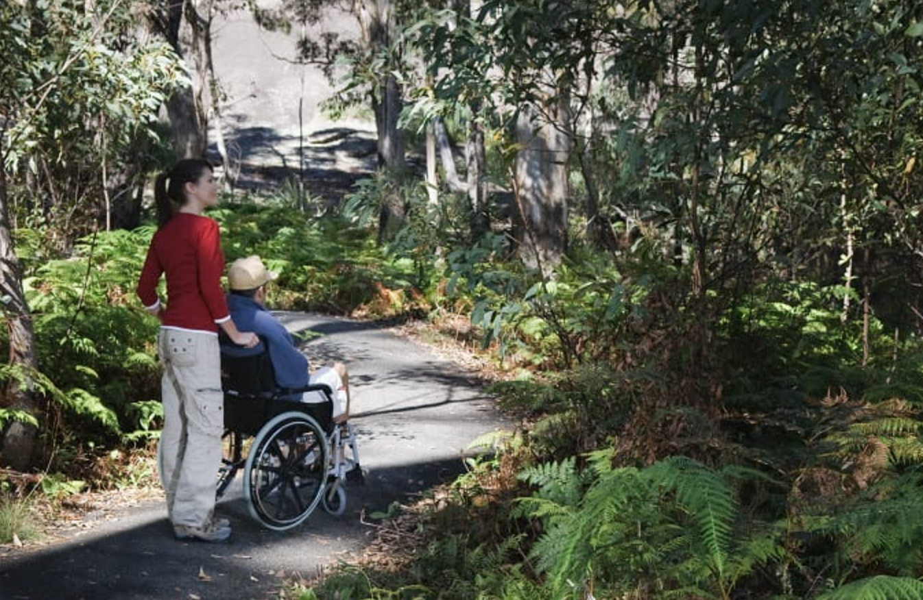 Woman and a man in a wheelchair going for a walk through nature