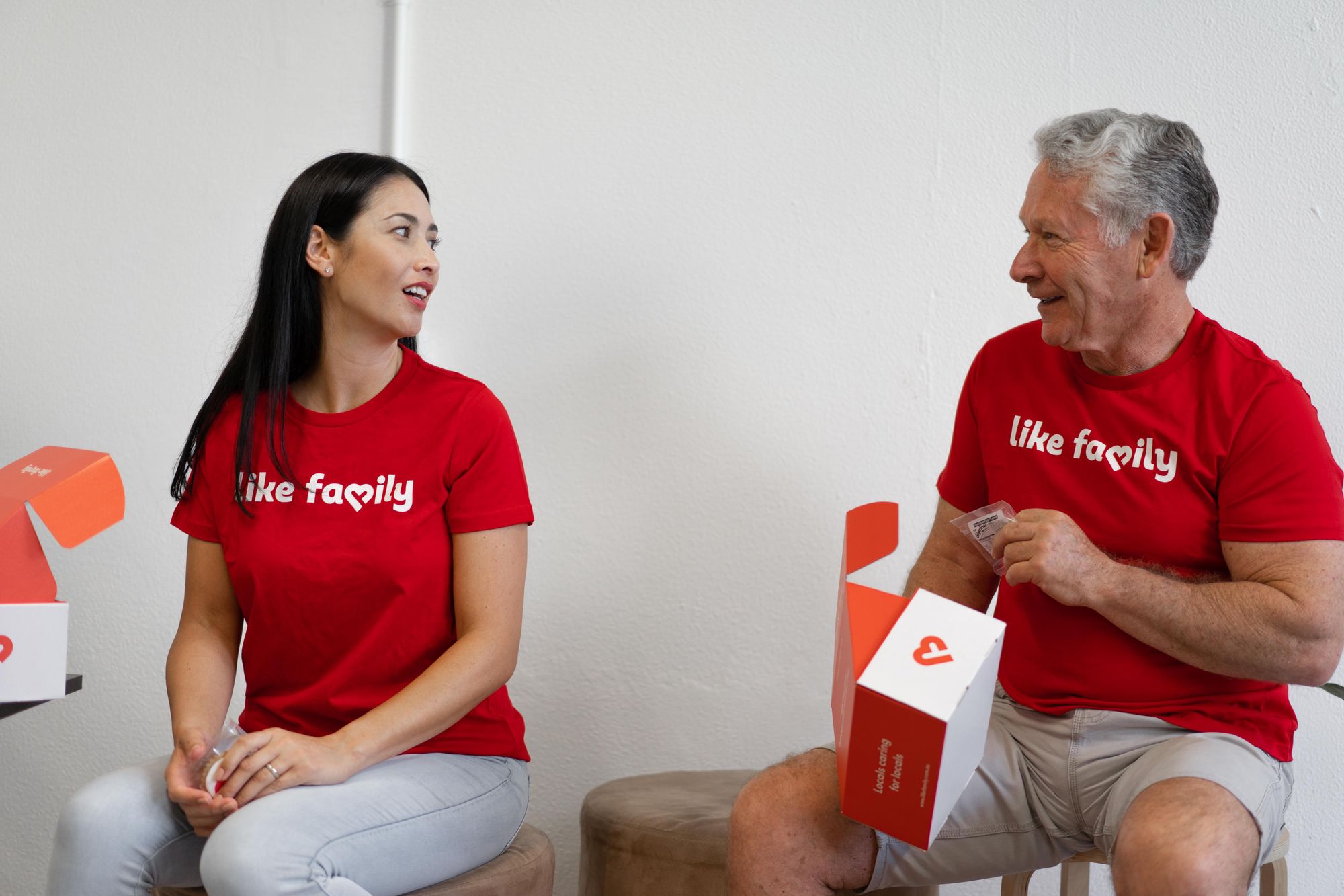 A woman and a man wearing red Like Family t-shirts