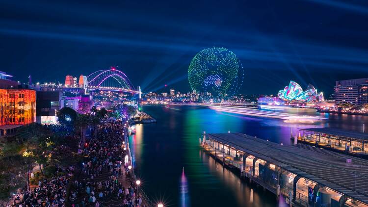 Landscape picture of the Sydney Harbour at night displaying a drone show.