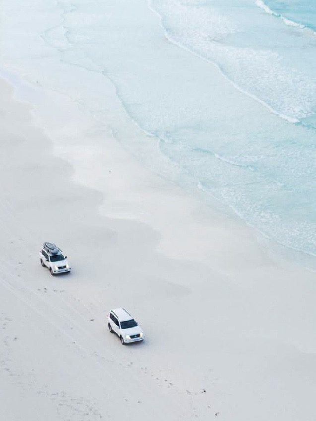 Cars driving along a white Western Australian beach