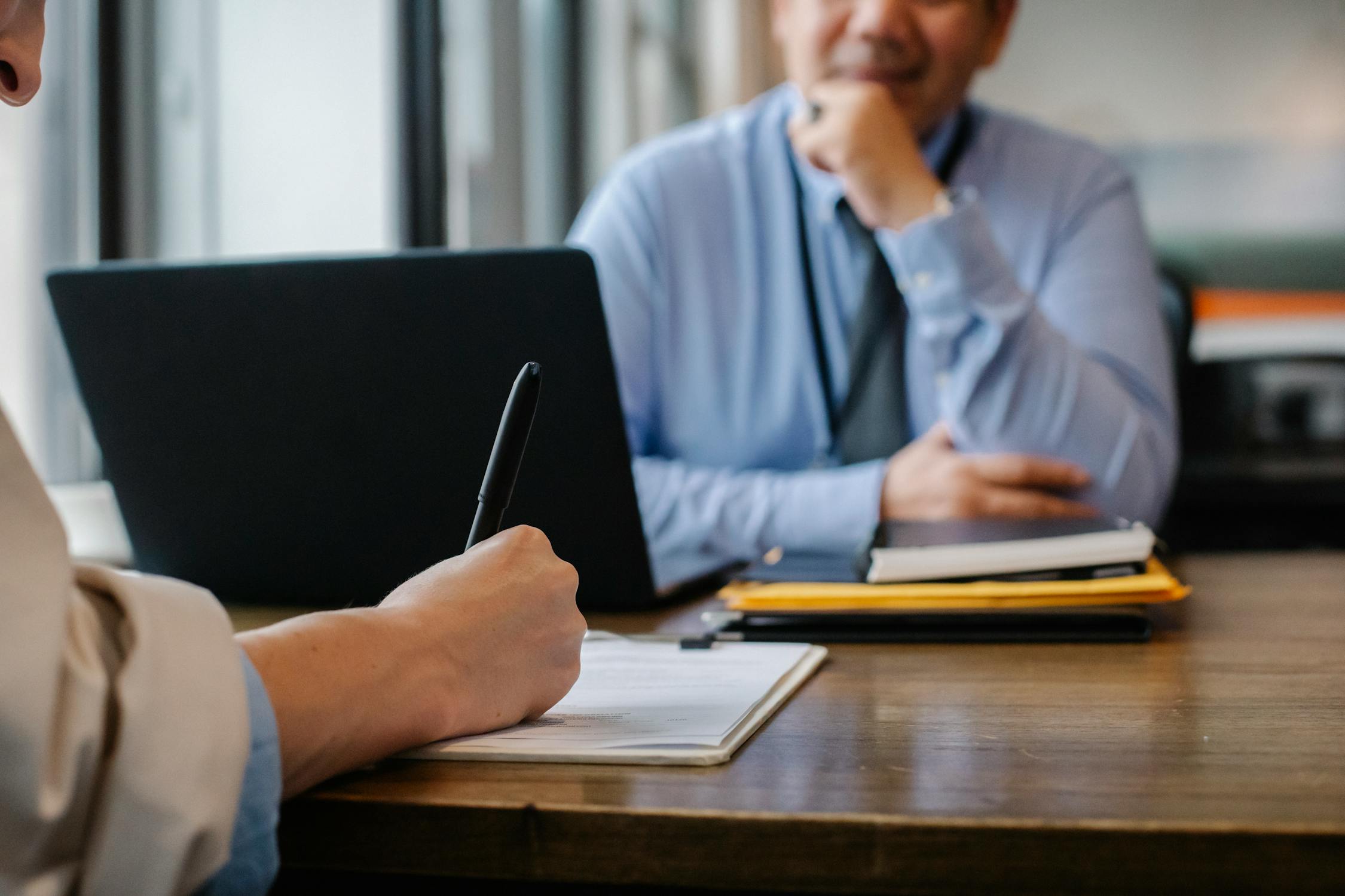 two people sitting across a desk signing some documents