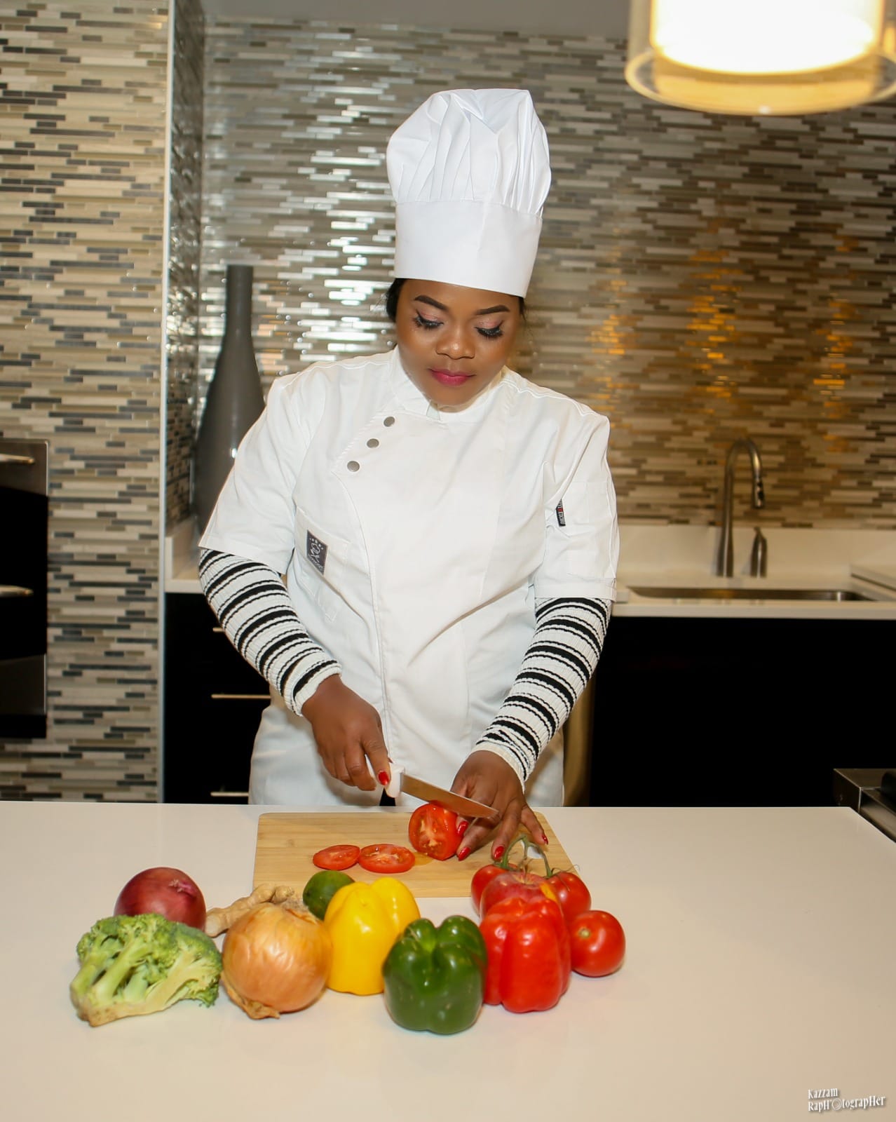 Chef MayaMoyo smiling and cutting vegetables in a modern kitchen