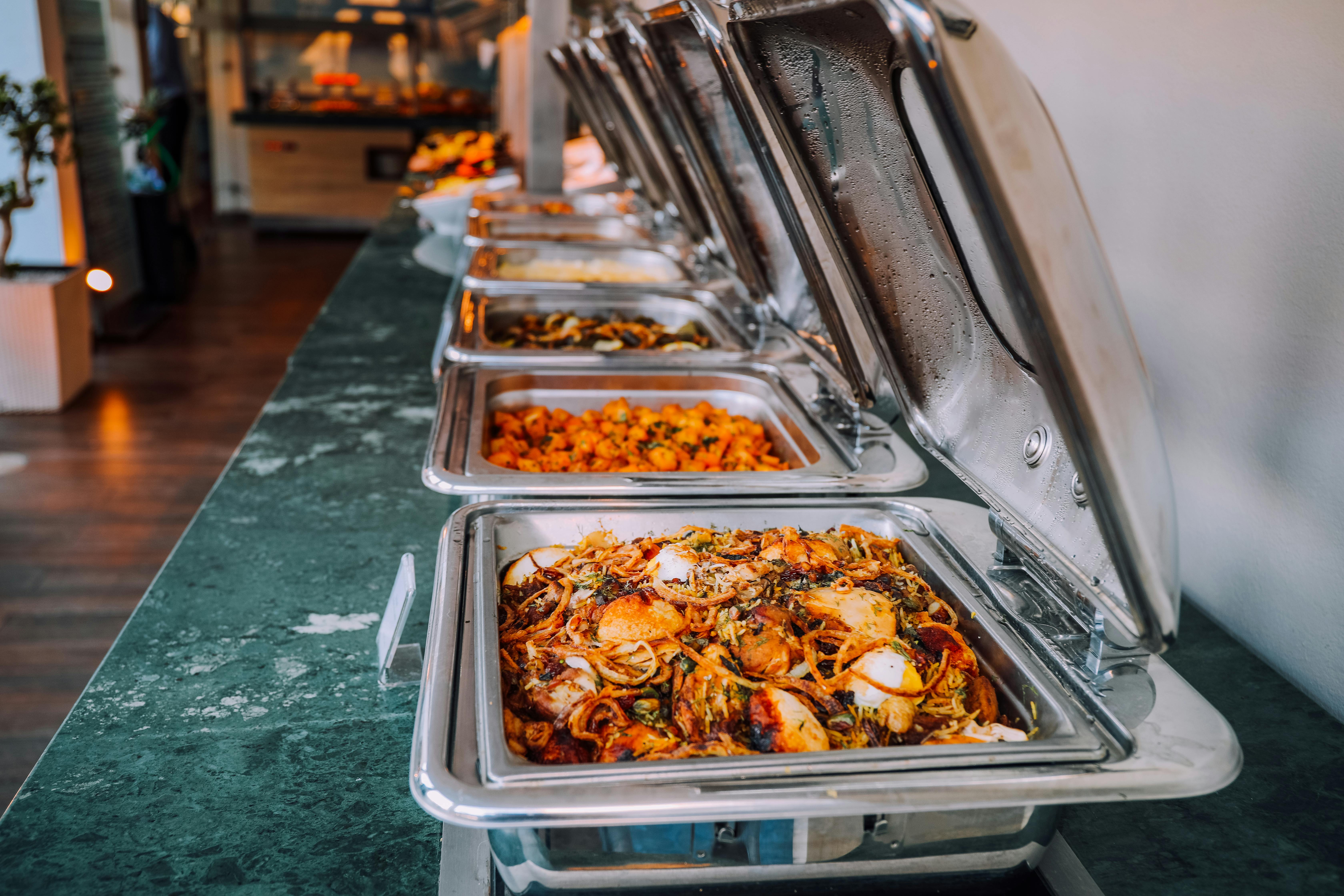 Catering setup with various West African dishes in chafing dishes