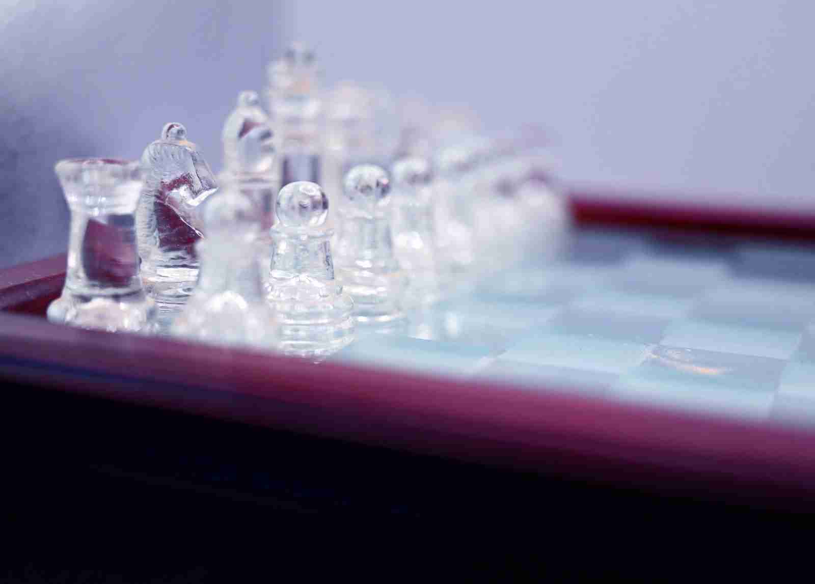 a glass chess set on a wooden table