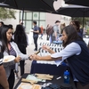 Volunteer handing out re-usable bamboo utensil sets to our students.