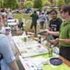 UAB Recycling Coordinator Jon Paolone shows Earth Day patrons a plastic disc & rubber jar opener made of recycled materials while student assistant Mustafa Muneer looks on.