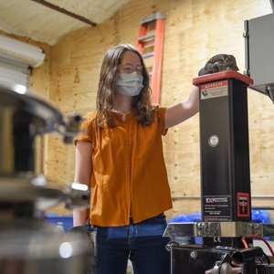 Senior Ally Esmond feeds a bottle into the glass crushing machine.