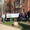 volunteers and Grounds crew members stand happily by the Tree Campus USA banner.