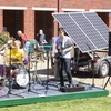 Student band "Corporate Stepdads" performs on a stage powered by solar panels.