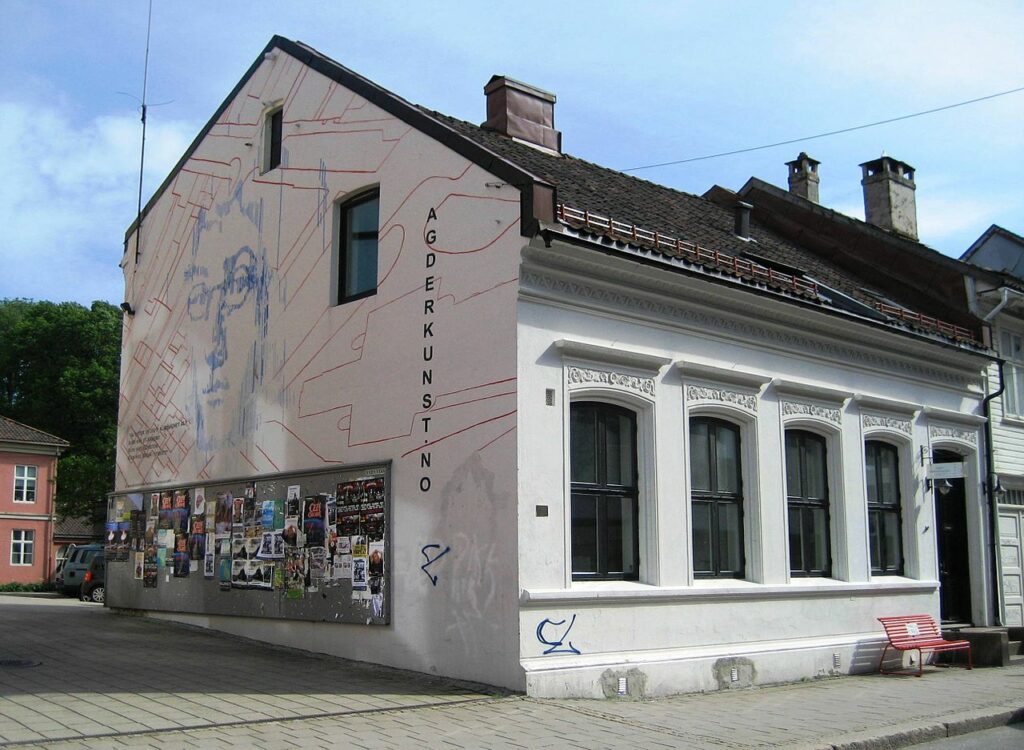 🎨🏛️ Agder Kunstsenter 🏛️🎨 En møteplass for kunstelskere Agder Kunstsenter ligger i hjertet av Kristiansand og er et kulturelt knutepunkt for samtidskunst i regionen. Bygget, som kombinerer historisk sjarm med moderne kunst, byr på utstillinger, arrangementer og prosjekter som fremmer kunst og kultur i Agder. Besøkende kan også oppleve unike verk fra lokale og internasjonale kunstnere, og stedet er perfekt for kunstelskere på oppdagelsesferd. Utforsk nabolaget rundt for en komplett kulturopplevelse. Foto: Agnesr, CC BY-SA 3.0 https://creativecommons.org/licenses/by-sa/3.0 agder-kunstsenter-kristiansand Agder Kunstsenter – Historisk og Samtidskunst i Kristiansand Agder Kunstsenter, Agder Kunstsenter Kristiansand, Agder Art Center, Agder Kunst Center, Agder Kunstcenter, Kristiansand Kunstsenter, Sørlandet Kunstsenter, Southern Norway Art Center, Agder Kunst, Kristiansand Kultur, Kunst Sørlandet