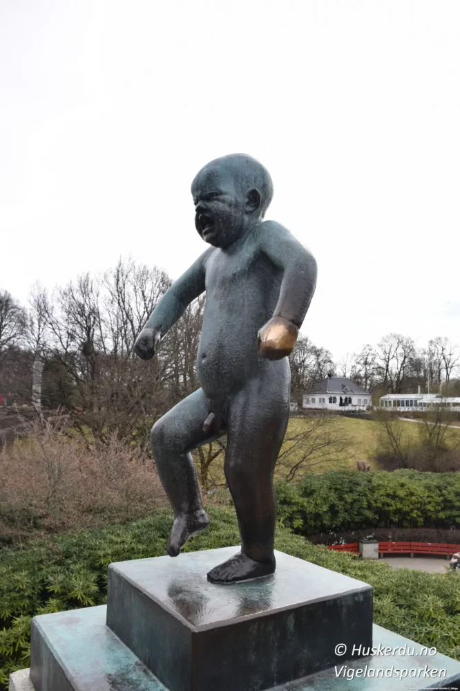 Sinnataggen – En av Norges mest kjente skulpturer Sinnataggen er en ikonisk bronsestatue i Vigelandsparken i Oslo, skapt av Gustav Vigeland. Skulpturen viser en liten gutt med et bestemt og sint uttrykk, kjent for å symbolisere barnets følelser og trass. Figuren er blitt et av de mest populære motivene i parken og et yndet fotosted for turister fra hele verden. Detaljbilder viser hånden og foten til Sinnataggen, som har blitt skåret av flere ganger gjennom historien, men alltid restaurert til sin opprinnelige form. Skinnende partier på statuen avslører hvor tusenvis av besøkende har berørt den i årenes løp, spesielt hånden, som er blitt et symbol på lykke. Sinnataggen står som en sterk representasjon av menneskelige følelser og en viktig del av Vigelands livsverk. Foto: © Huskerdu.no