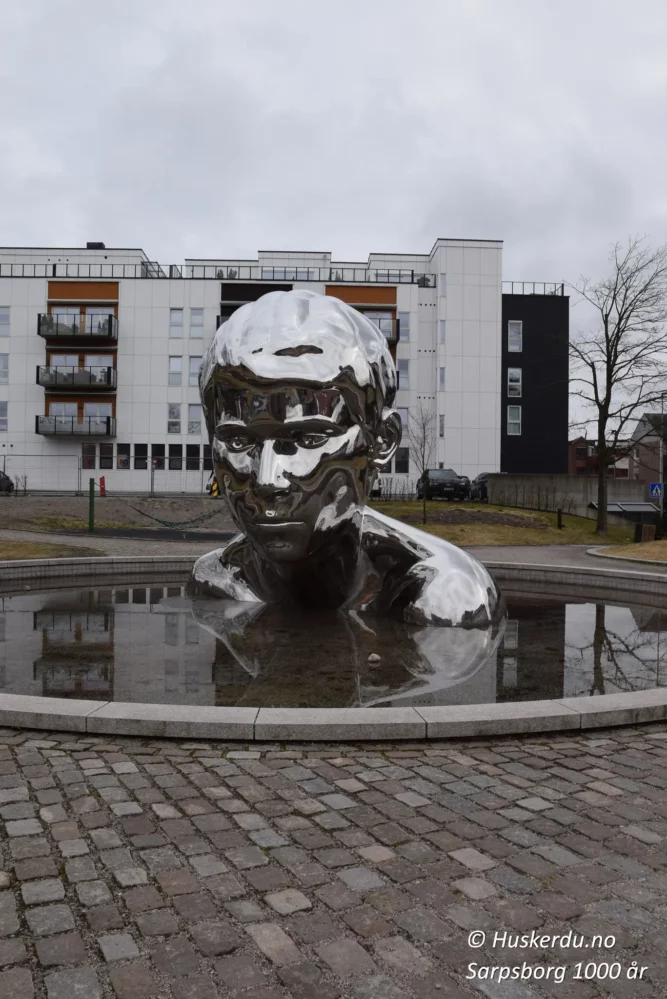 🎨🛡️ GENESIS – Den unge Olav 🛡️🎨 Skulpturen «GENESIS» i Sarpsborg er et kunstverk laget av billedkunstner Finn Eirik Modahl i samarbeid med Arne Revheim. Den ble gitt som en gave fra Sparebankstiftelsen DNB til byens tusenårsjubileum i 2016. Skulpturen symboliserer Sarpsborgs grunnlegger, Kong Olav Haraldsson, som etablerte byen i 1016. Refleksjonene i den blanke overflaten gir et moderne preg på byens rike historie og vikingarv. Foto: © Huskerdu.no https://huskerdu.no GENESIS – Den unge Olav i Sarpsborg Sarpsborg, Sarpsborg 1000 år, Genesis skulptur, Genesis Sarpsborg, Olav Haraldsson statue, Sarpsborg kunst, Sarpsborg historie, Sarpsborg jubileum, Sarpsborg sentrum, Sarpsborg vikingarv, Olav den hellige Sarpsborg