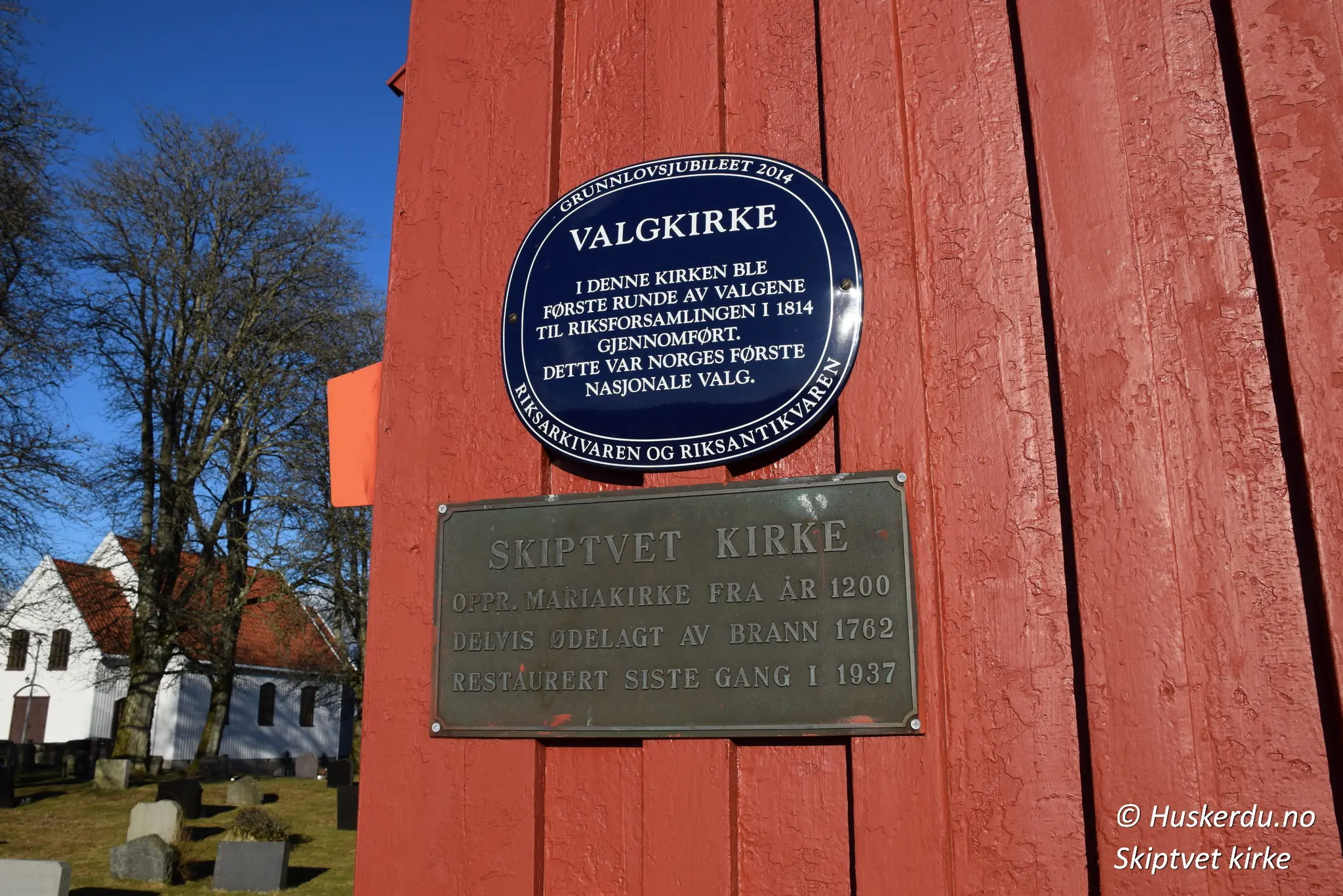 🏰 Skiptvet Kirke 🏰 🗳️ Historisk Valgkirke 🗳️ Skiltet ved Skiptvet kirke markerer dens rolle som valgkirke under Norges første nasjonale valg i 1814. Her ble den første runden av valgene til riksforsamlingen på Eidsvoll gjennomført. Kirken, opprinnelig bygget rundt år 1200, har en lang historie som inkluderer gjenoppbygging etter en brann i 1762 og restaurering i 1937. Dette gjør den til både et religiøst og nasjonalt monument med dype røtter i norsk historie. Foto: Huskerdu.no skiptvet-kirke-valgkirke-historisk-monument Skiptvet Kirke – Valgkirke og Historisk Monument Skiptvet kirke, valgkirke 1814, Skiptvet middelalderkirke, Østfold kirker, Eidsvoll valgkirker, norsk historie, nasjonale valg, kirker i Norge