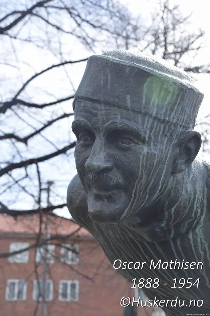 Oscar Mathisen – Skøytesportens ansikt i bronse Et nærbilde av statuen ved Frogner Stadion i Oslo, laget av Arne Durban i 1959. Oscar Mathisen, en av Norges største skøyteløpere, er udødeliggjort i dette kunstverket, som fanger hans fokus og lidenskap for sporten. Mathisen var kjent for sin utholdenhet og satte hele 14 verdensrekorder i løpet av sin karriere. Foto: Huskerdu.no