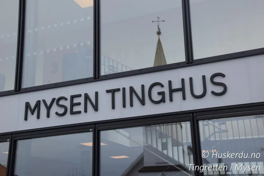 Mysen Tinghus – Fasadeskil Fasaden til Mysen Tinghus med tydelig skilt og reflekser fra nærliggende bygninger.Mysen Tinghus, Follo tingrett, Nordre Østfold tingrett, tingrettsbygning, tinghus skilt, domstol Østfold, rettslokale, rettsvesen, domstol Norge, tinghuset Mysen