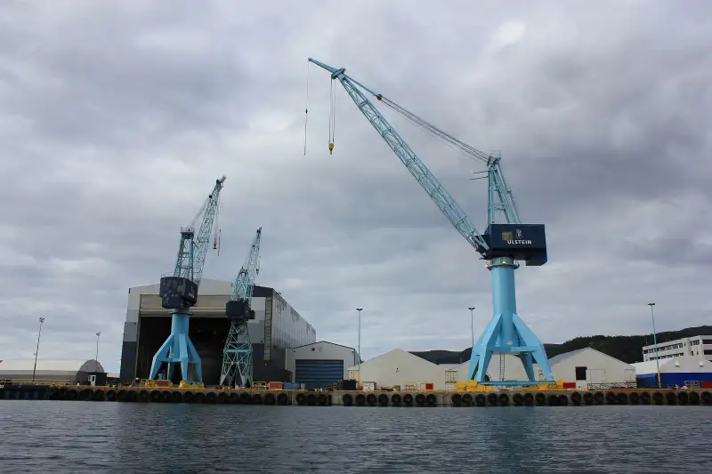 Kranene ved Ulstein Verft ⚙️ Store skipsverftkraner reiser seg over dokkanleggene til Ulstein Verft, et av Norges mest kjente verft for bygging av avanserte skip. Den blå kranen med Ulstein-logoen dominerer havneområdet og markerer en stolt maritim tradisjon. Bildet viser den industrielle delen av Ulsteinvik, der store fartøy får form langs kysten av Møre og Romsdal. Foto: Sundgot, CC BY-SA 3.0 https://creativecommons.org/licenses/by-sa/3.0 https://commons.wikimedia.org/wiki/File:Ulstein_verft_AS_9.jpg 800-px-kranene-ved-ulstein-verft-i-ulsteinvik Ulstein Verft – Kraner og skipsverft i Ulsteinvik ulsteinvik, ulstein verft, skipsverft, industri, kran, ulstein kommune, verftskran Ulstein kommune