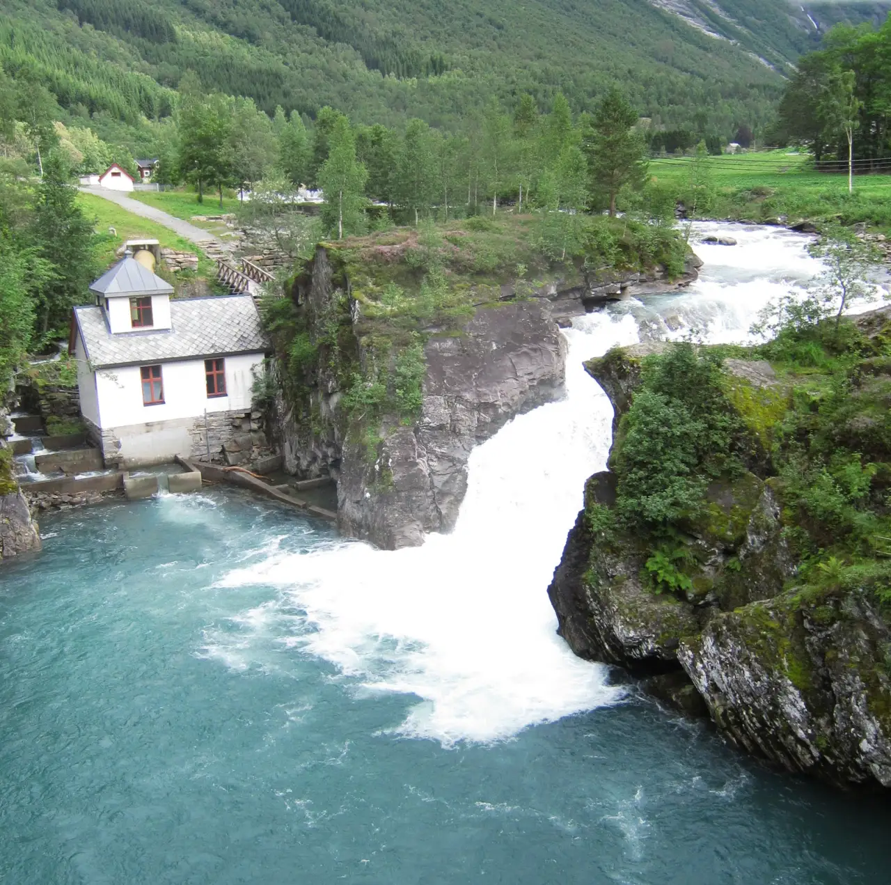 Holsfossen og laksetrappa i Valldal 🐟 Langs elva Valldøla finner du Holsfossen, et kraftig fossefall som har vært brukt til kraftproduksjon i over hundre år. Bildet viser det historiske kraftverket og laksetrappa som ble bygd for å hjelpe villaksen trygt opp fossen. Denne delen av Valldal kombinerer vakker natur med lokal teknologihistorie og er lett tilgjengelig fra hovedveien. Foto: Tourist, CC BY-SA 3.0 https://creativecommons.org/licenses/by-sa/3.0 https://commons.wikimedia.org/wiki/File:Holsfossen_kraftverk_laksetrapp.JPG holsfossen-kraftverk-og-laksetrapp-i-valldal Holsfossen og laksetrappa i Valldal valldal, valdahl, valldahl, valldøla, holsfossen, laksetrapp, kraftverk, foss, valldal kraft Fjord kommune