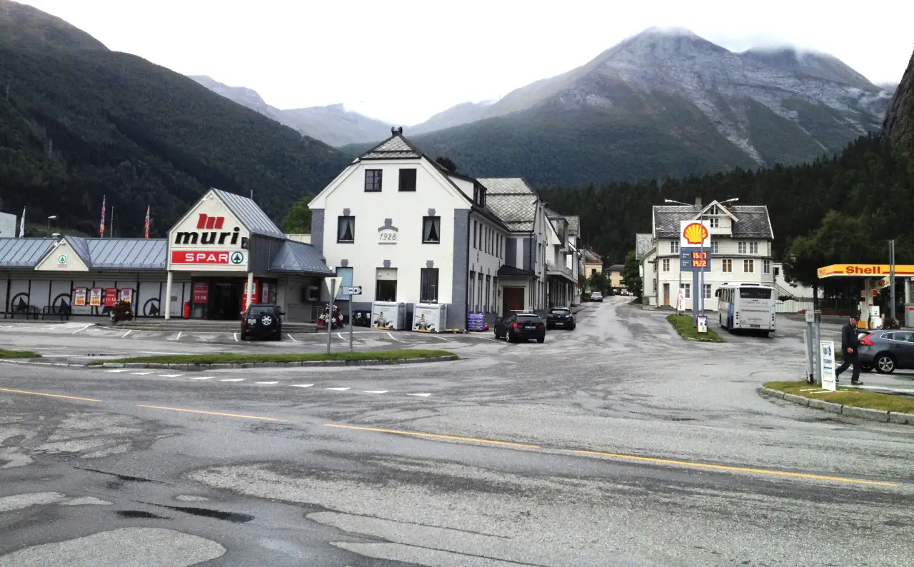 Sentrumsgata i Valldal 🏘️ Sylte er det livlege sentrumet i Valldal og kommunesenter for Fjord kommune. Her ligg både daglegvarebutikk, bensinstasjon og overnattingstilbod, omgitt av høge fjell som rammar inn bygda dramatisk. Mange reisande på veg mellom Geiranger og Trollstigen stoppar nettopp her for ein pause, overnatting eller for å handle lokale bær og produkt frå dalen. Foto: Kjetil Ree, CC0 https://creativecommons.org/publicdomain/zero/1.0/ https://commons.wikimedia.org/wiki/File:Valldal_Sept_2014.jpg sentrumsgata-i-valldal-med-fjell Sentrumsgata i Valldal med fjell i bakgrunnen valldal, valdall, valdal, sentrum, sylte, fjordkommune, butikk, fjell Fjord kommune