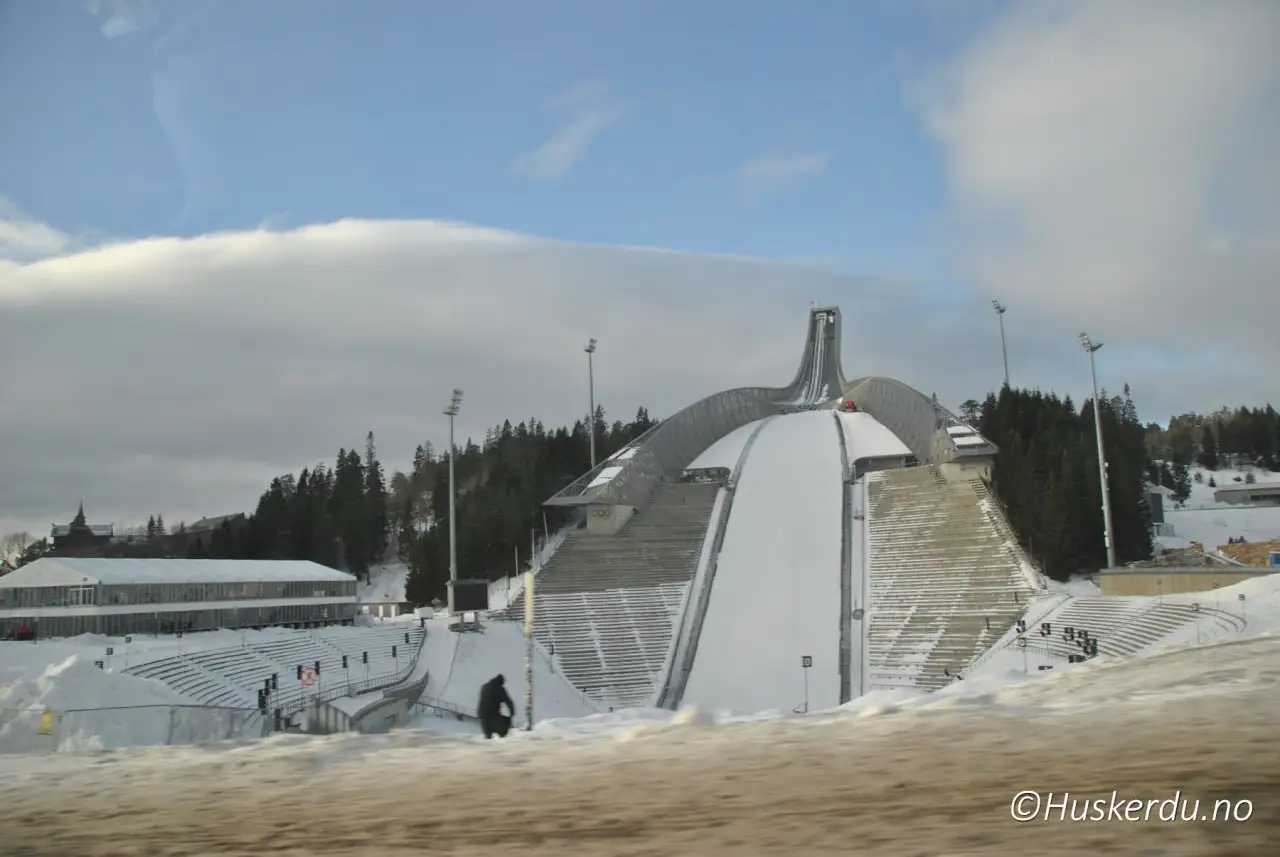 Holmenkollen hopparena ⛷️ Holmenkollen reiser seg som et av Norges mest kjente landemerker, omgitt av grønn skog og tribuner som kan ta imot tusenvis av tilskuere. Den moderne hoppbakken brukes til store konkurranser og er et populært reisemål året rundt, både for sportsinteresserte og turister som vil oppleve utsikten over Oslo fra toppen. Foto: © Huskerdu.no Holmenkollen hopparena – Utsiktspunkt og idrettsanlegg. Foto: © Huskerdu.no kollensvevet-45-28-07-2024-huskerdu Holmenkollen hopparena – Skibakke og utsikt over Oslo Holmenkollen, Holmenkollen Oslo, Holmenkollen hoppbakke, Holmenkollen arena, Holmenkollen ski jump, Oslo landemerker, hopparena i Oslo, Kollensvevet, Oslo vinter, Oslo turmål Oslo Kommune