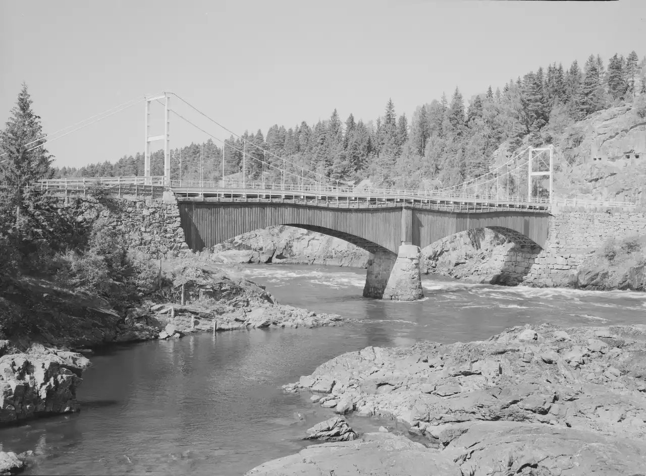 Fossum bru ved Glomma 🌉 Fossum bru mellom Askim og Spydeberg ble lenge regnet som en av Østfolds vakreste veibroer. Den elegante stålkonstruksjonen binder landskapet sammen over Glomma og har vært et viktig krysningspunkt siden tidlig 1900-tall. Under kampene i april 1940 spilte området en sentral rolle da norske styrker forsøkte å stanse de tyske troppene som rykket østover fra Oslo. I dag står brua som et stille vitne til både ingeniørkunst og historie. Foto: Jac Brun / Mittet & Co. AS / Nasjonalbiblioteket - Public Domain https://www.nb.no/lisens/#public-domain https://urn.nb.no/URN:NBN:no-nb_digifoto_20150219_00125_NB_MIT_FNR_16421 fossum-bru-askim-glomma-1956 Fossum bru over Glomma mellom Askim og Spydeberg fossum, fossum bru, fossumbro, glomma, askim, spydeberg, østfold, fossum bridge, norge bru, glommakryssing Indre Østfold kommune