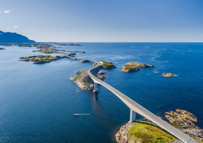 Atlanterhavsveien slynger seg over lave bruer mellom holmer og skjær ytterst i havet på Averøy.