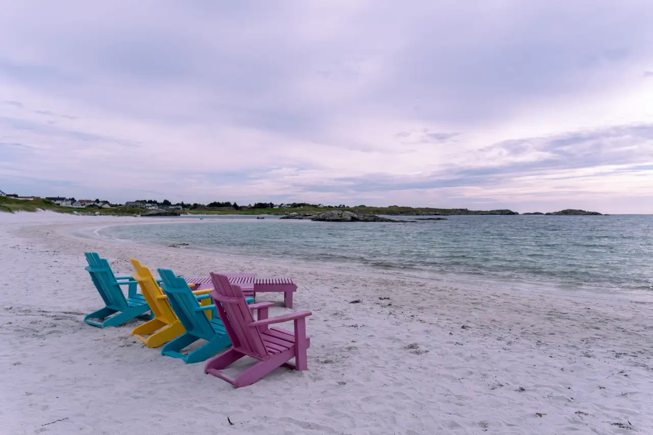 Strandstoler på Åkrasanden vendt mot havet med kystlandskap i bakgrunnen.