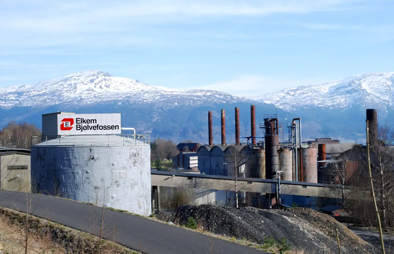 Elkem Bjølvefossen i Ålvik med industribygg og skorsteiner foran snødekte fjell i Kvam kommune