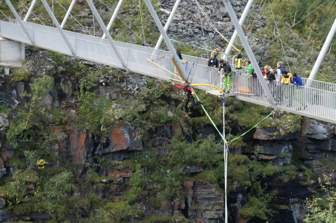 Strikkhopper tar sats fra plattformen under Gorsa Bridge mens publikum ser på og canyonen åpner seg under.