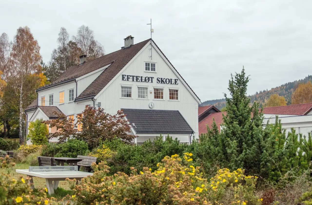 Efteløt skole med uteområde og boligområder rundt langs hovedveien i bygda.