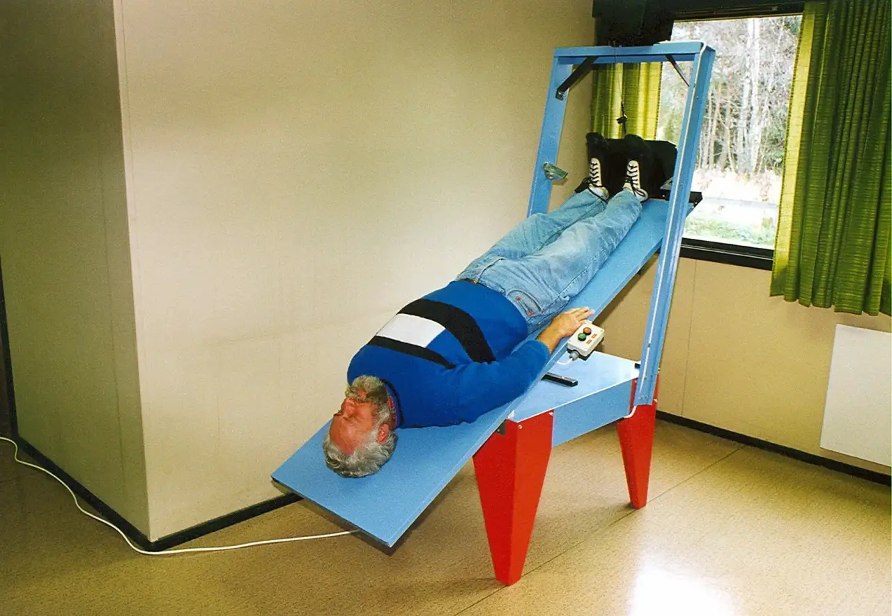 Askim – Erling Olsen tester Rolf Mosebys motoriserte strekkbenk for ryggavlastning på midten av 1980-tallet.