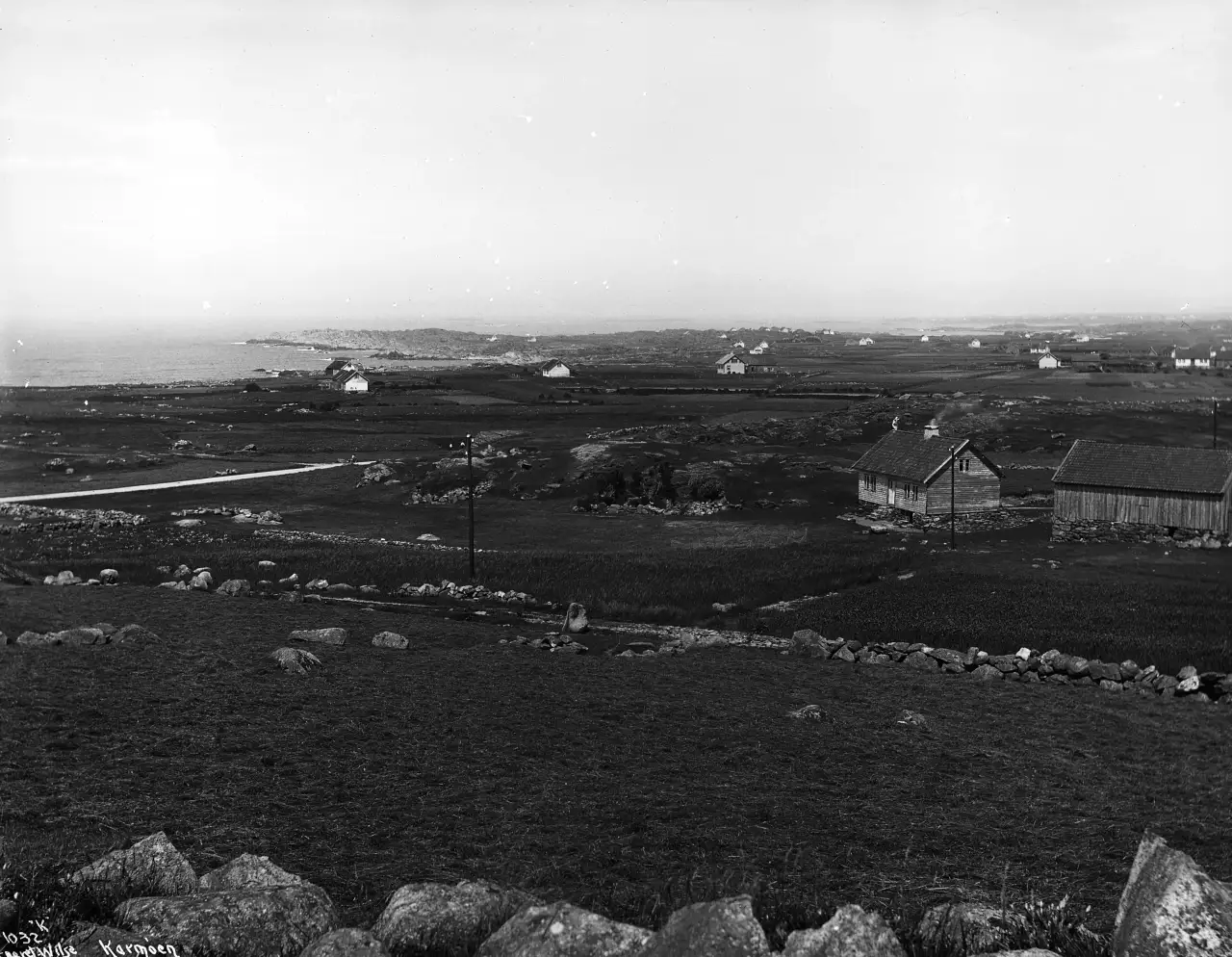 Panorama over Ferkingstad i 1913 med åpne jorder, gårdsbebyggelse og kystlandskap mot havet.
