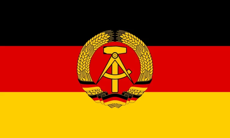 Flagget til DDR med hammer, passer og kornkrans på svart, rødt og gult bakgrunnsfelt.