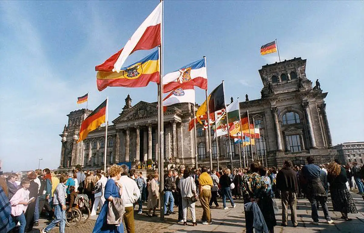 Mennesker og flagg samlet foran Reichstag i Berlin under den fredelige tyske gjenforeningen 3. oktober 1990.