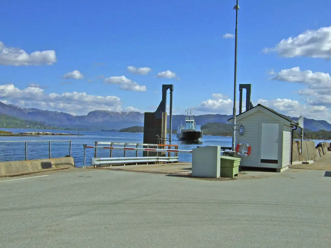 Fure ferjekai med ferge på vei inn mot kaia og fjellandskap i bakgrunnen.