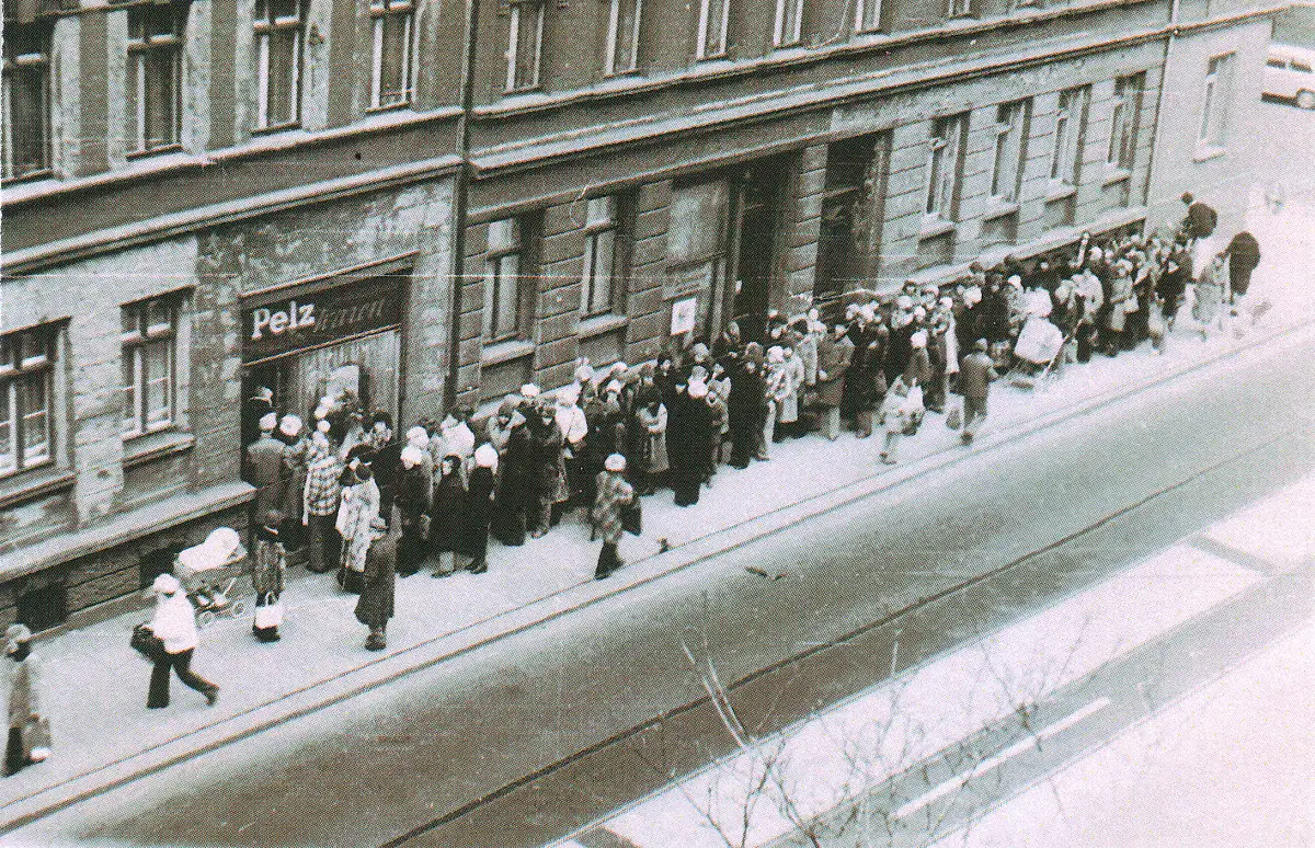 Lang kø av mennesker utenfor en butikk i Leipzig som venter på å kjøpe kaninluer under vareknapphet i DDR på 1980-tallet.