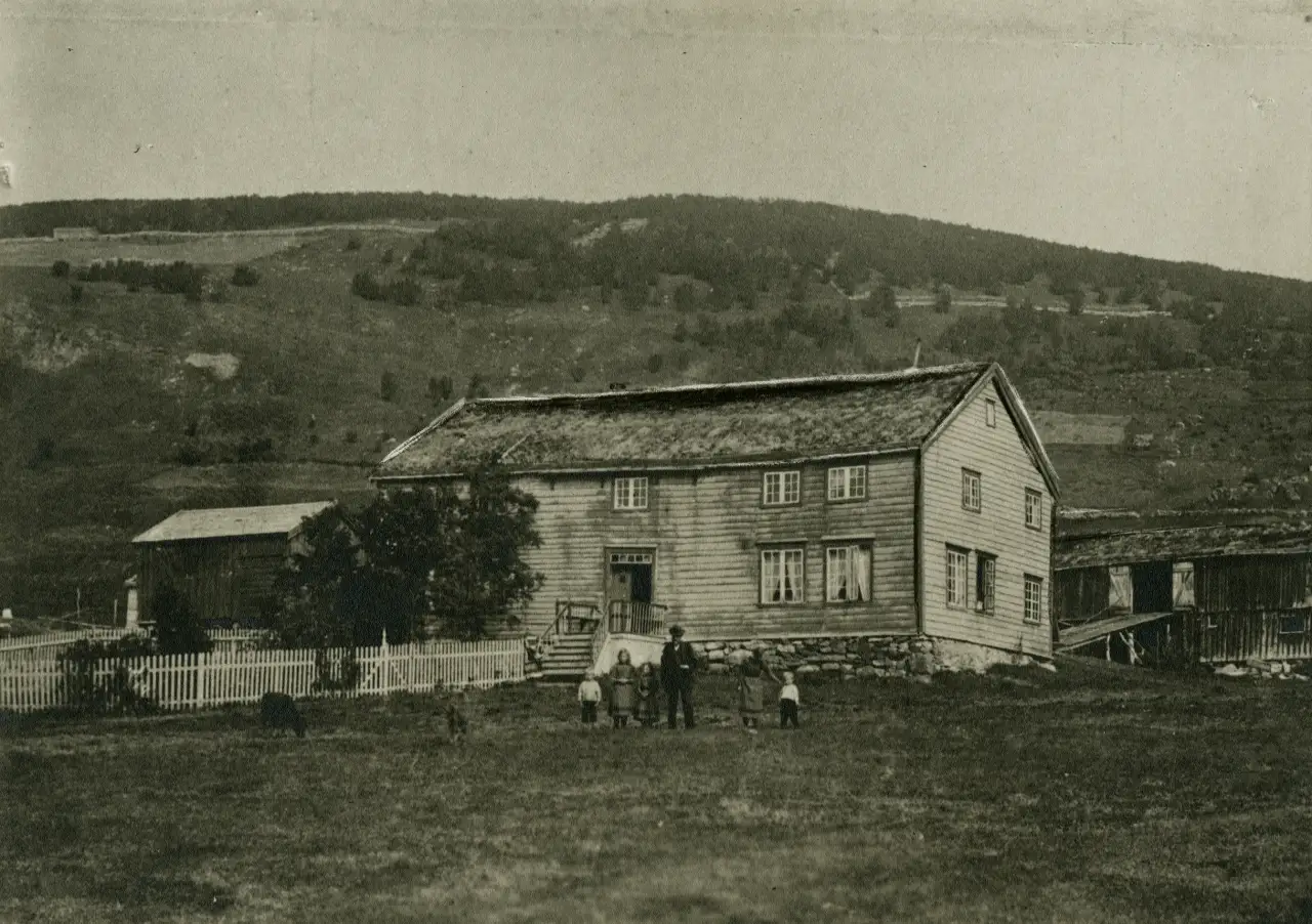 Kvæfjord prestegård på Rå med hovedbygning og tun omgitt av beiteland og skogkledde åser.