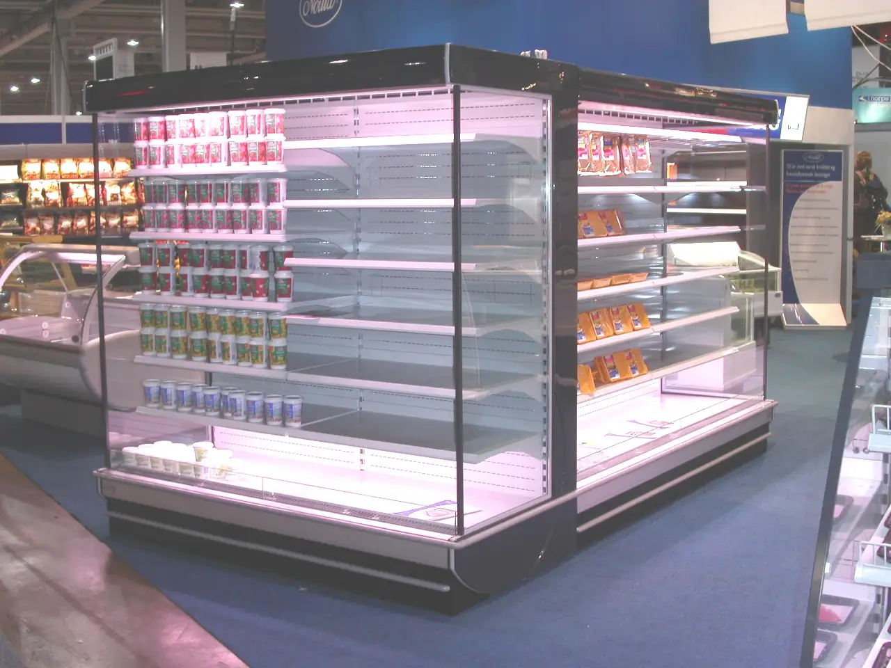 Kjøletorg fra Norild modell 2100 ❄️ Et kjøletorg fra Norilds prisbelønte modell 2100-serie utstilt på kjølemessen. Diskens seks plan og åpne konstruksjon gjorde den velegnet til ferskvare og pålegg, med piggheng på høyre side for ferdigpakkede produkter. Norild utviklet selv designet i Askim, men begynte på denne tiden å kjøpe inn enkelte komponenter som hyller og lyskasser for å øke produksjonskapasiteten uten flere ansatte. Foto: Bjørn Sandbæk / © Huskerdu.no norild-6-plan-torg-mod-2100 Kjøletorg fra Norild modell 2100 på kjølemessen Norild, Norild Apparatfabrikk, Modell 2100, kjøletorg, kjøledisk, ferskvaredisk, kjølemøbler, Askim, Østfold