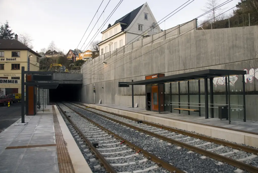 Paradis holdeplass på Bybanen i Fana med plattformer, spor og tunnelåpning.