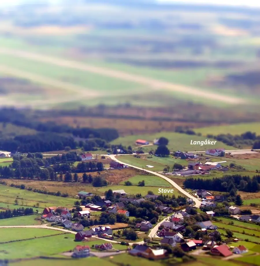 Stava og Langåker sett fra luften med spredt bebyggelse og jordbruksområder i et åpent landskap.