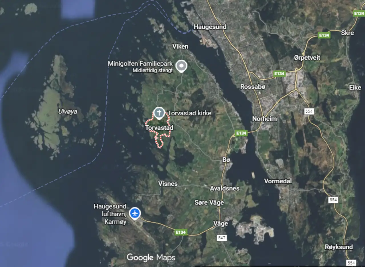 Torvastad sett fra satellitt med boligområder grøntområder og Karmsundet i bakgrunnen.